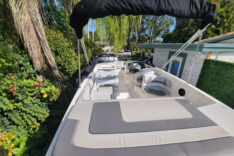 Slide: The Image of 2023 Bayliner VR6 Bowrider OB boat with spacious seating and canopy, surrounded by lush greenery. - 11