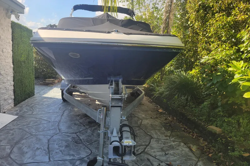 The Image of 2023 Bayliner VR6 Bowrider OB on trailer, parked on a stone driveway. - 1