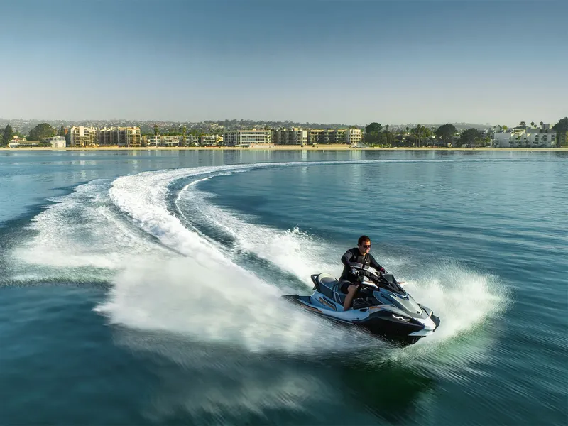 Slide: The Image of A man rides a Kawasaki Jet Ski® STX® 160LX on calm water near a coastal city. - 18