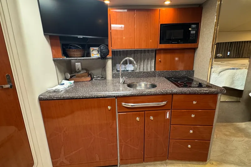 Slide: The Image of 2004 Formula 37 Performance Cruiser kitchen with wood cabinets, sink, stove, and microwave. - 19
