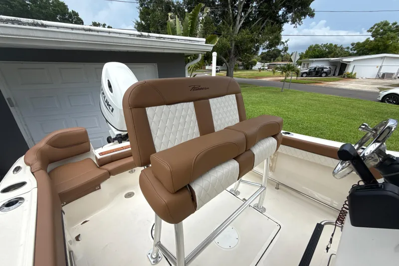 Slide: The Image of 2023 Pioneer 202 Islander boat interior with brown and white seating, Suzuki engine visible. - 8