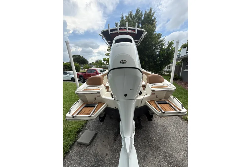 Slide: The Image of 2023 Pioneer 202 Islander boat, rear view with outboard motor and seating, parked outdoors. - 17