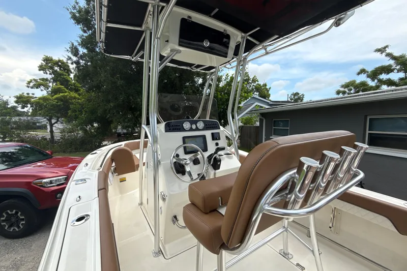 Slide: The Image of 2023 Pioneer 202 Islander boat interior with steering console and seating, parked outdoors. - 3