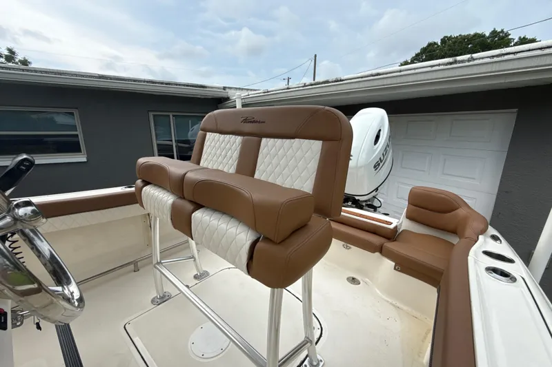 Slide: The Image of 2023 Pioneer 202 Islander boat with brown and white seating, parked near a garage. - 7
