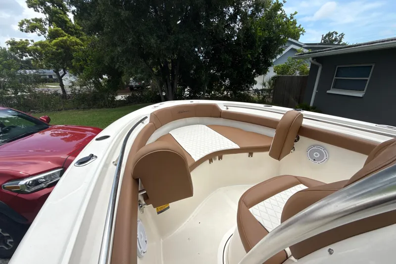Slide: The Image of 2023 Pioneer 202 Islander boat interior with brown and white seating, parked near a red car. - 11