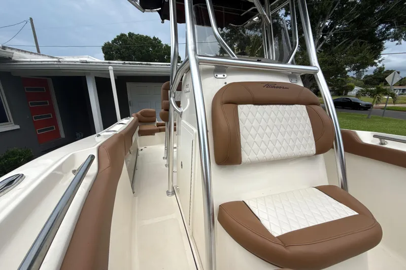 Slide: The Image of 2023 Pioneer 202 Islander boat with brown and white seating, parked near a house. - 13