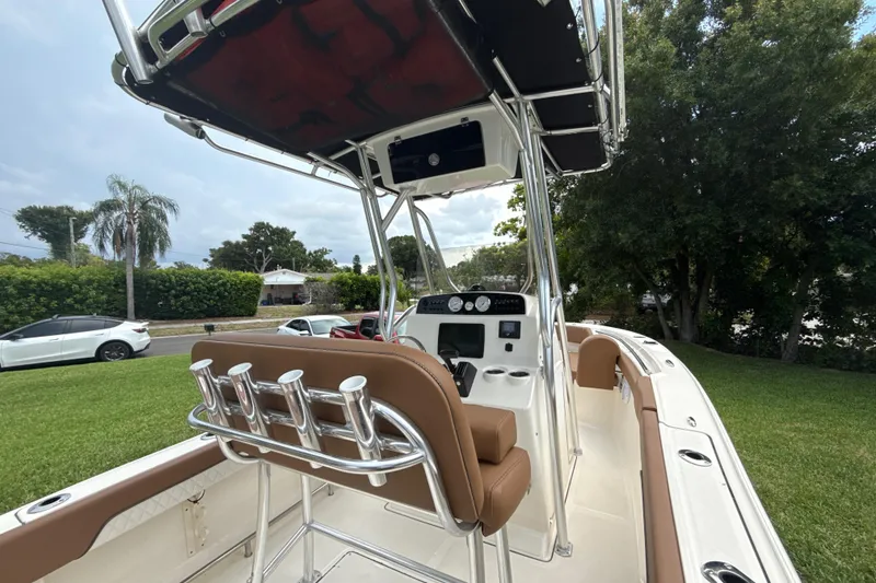 Slide: The Image of 2023 Pioneer 202 Islander boat with brown seating and T-top, parked on grass. - 2