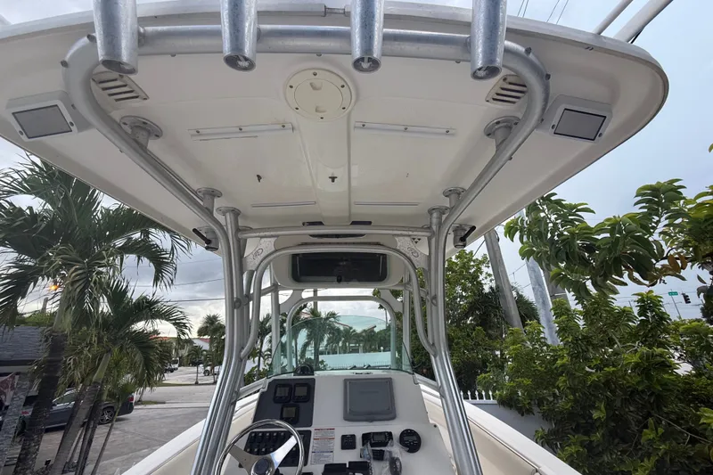 Slide: The Image of 2007 Robalo R260 Center Console boat with T-top and control panel, surrounded by tropical trees. - 56