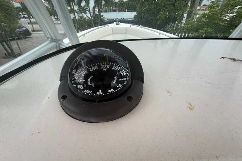 Slide: The Image of Compass on 2007 Robalo R260 Center Console boat, surrounded by lush greenery. - 54