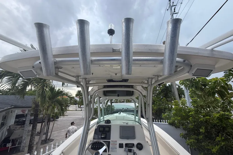 Slide: The Image of 2007 Robalo R260 Center Console boat with T-top and rod holders, docked near palm trees. - 57
