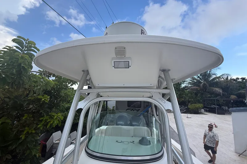 Slide: The Image of 2007 Robalo R260 Center Console boat with T-top, parked outdoors under a blue sky. - 30