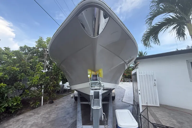 The Image of 2007 Robalo R260 Center Console boat on trailer, surrounded by tropical greenery. - 0