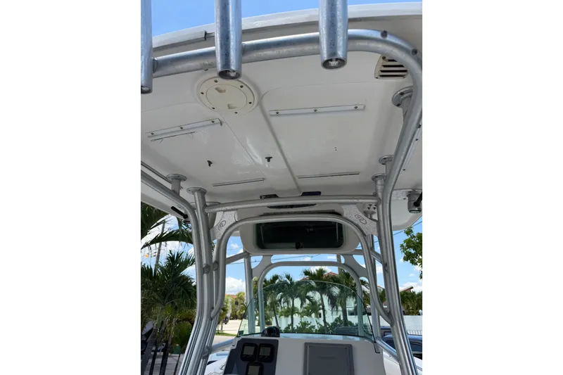 Slide: The Image of 2007 Robalo R260 Center Console boat with T-top and rod holders, docked near palm trees. - 5