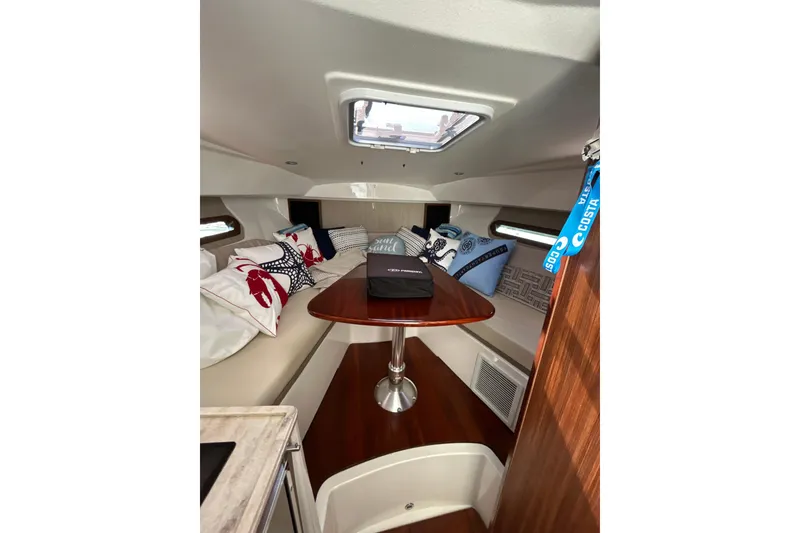 Slide: The Image of 2021 Pursuit OS 325 Offshore cabin interior with cozy seating and decorative pillows. - 15