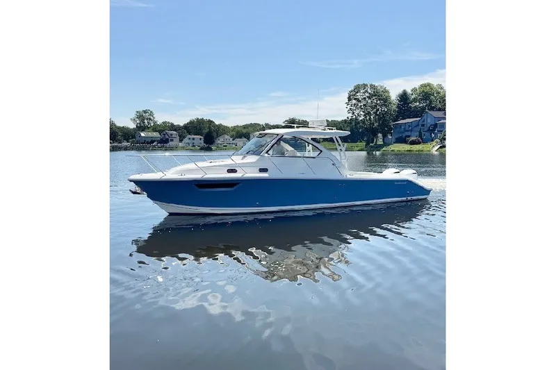 Slide: The Image of 2021 Pursuit OS 325 Offshore boat on calm water, with scenic background. - 10