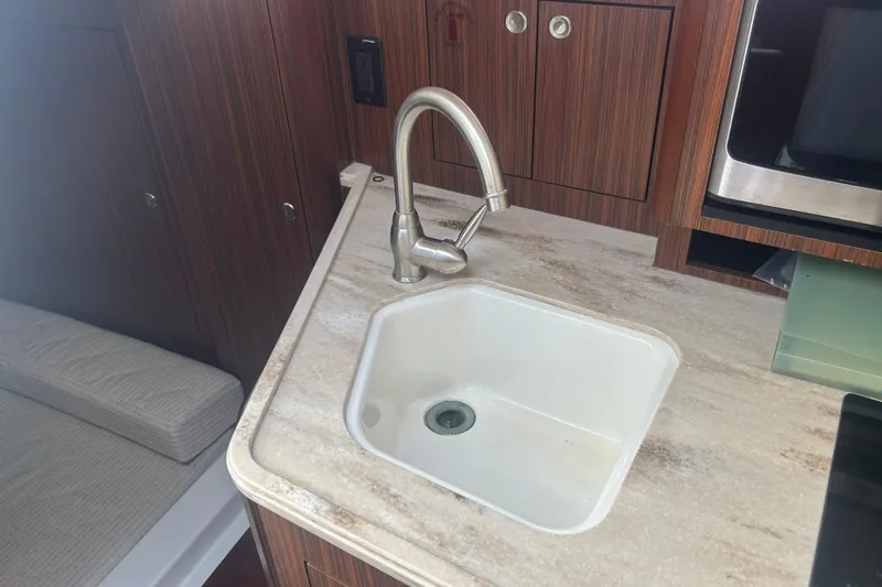 Slide: The Image of Modern kitchen sink in 2021 Pursuit OS 325 Offshore boat, featuring sleek faucet and wood cabinetry. - 16