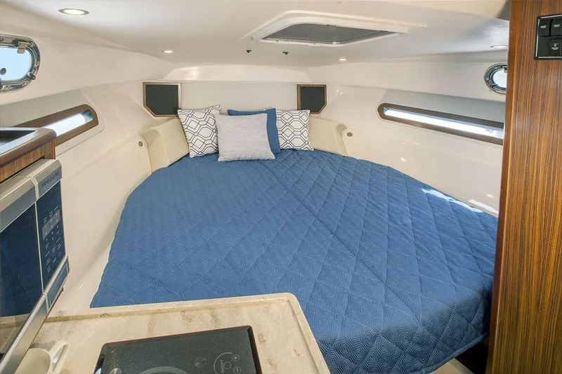 Slide: The Image of Manufacturer Provided Image: Interior cabin of 2021 Pursuit OS 325 Offshore with blue bedding and modern amenities. - 17