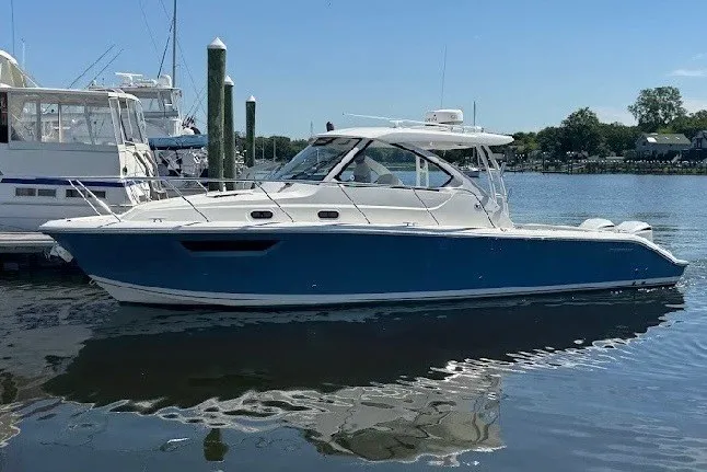 Slide: The Image of 2021 Pursuit OS 325 Offshore boat docked in a marina, featuring a sleek blue hull. - 3