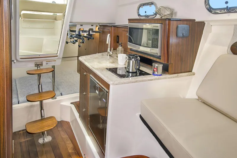 Slide: The Image of Manufacturer Provided Image: 2021 Pursuit OS 325 Offshore boat interior with kitchenette and seating area. - 12