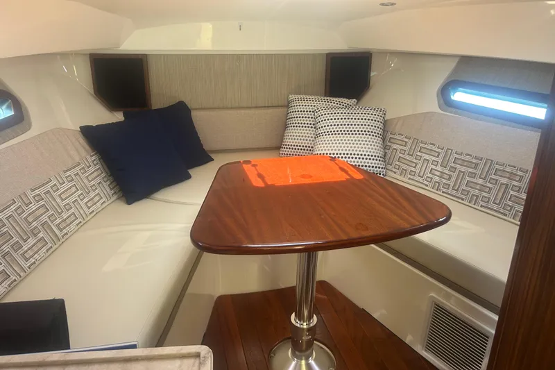 Slide: The Image of 2021 Pursuit OS 325 Offshore cabin interior with cushions and wooden table. - 5
