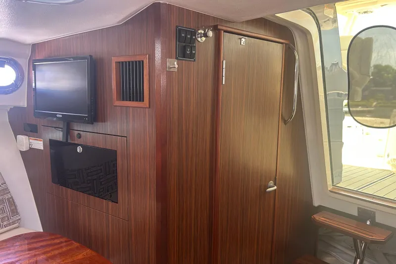 Slide: The Image of 2021 Pursuit OS 325 Offshore cabin interior with wood paneling and mounted TV. - 4