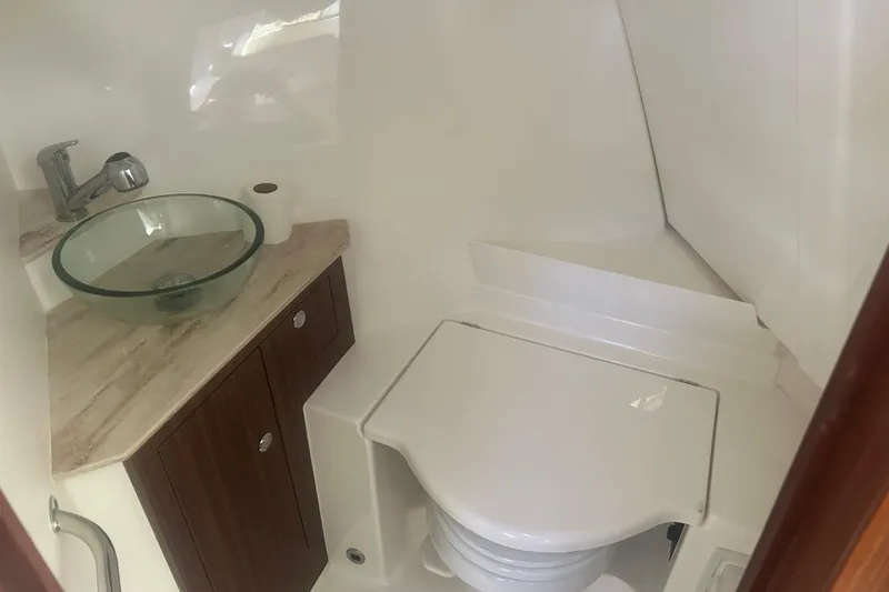 Slide: The Image of 2021 Pursuit OS 325 Offshore bathroom with glass sink and compact toilet. - 12
