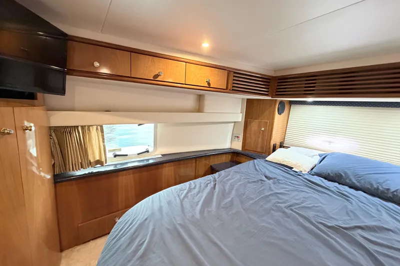 Slide: The Image of Luxurious 2003 Carver 396 Motor Yacht bedroom with wood cabinetry and cozy bedding. - 32