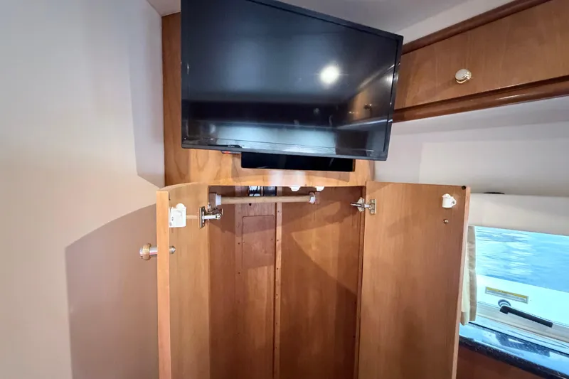 Slide: The Image of Interior of 2003 Carver 396 Motor Yacht with TV and open wooden cabinet. - 34