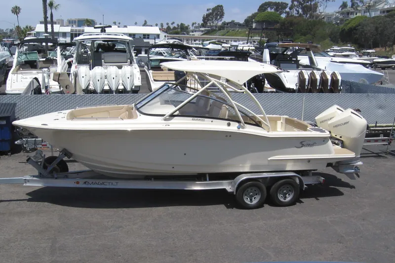 The Image of 2024 Scout 255 Dorado boat on trailer, parked in marina with other boats. - 1