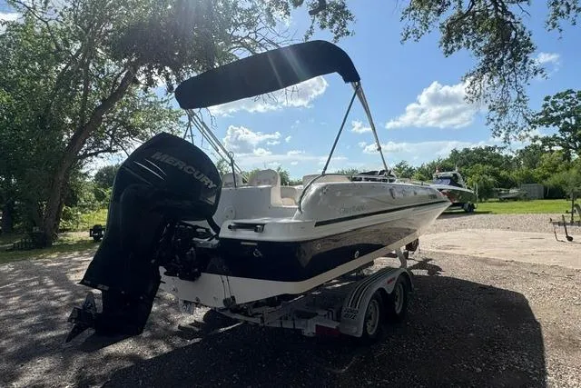 Slide: The Image of 1999 Hurricane SunDeck Sport 201 OB boat on trailer, parked outdoors under trees. - 5