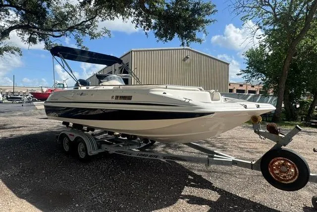 Slide: The Image of 1999 Hurricane SunDeck Sport 201 OB boat on trailer, parked outdoors under a blue sky. - 7