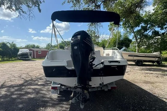 Slide: The Image of 1999 Hurricane SunDeck Sport 201 OB boat with outboard motor, parked outdoors under trees. - 4