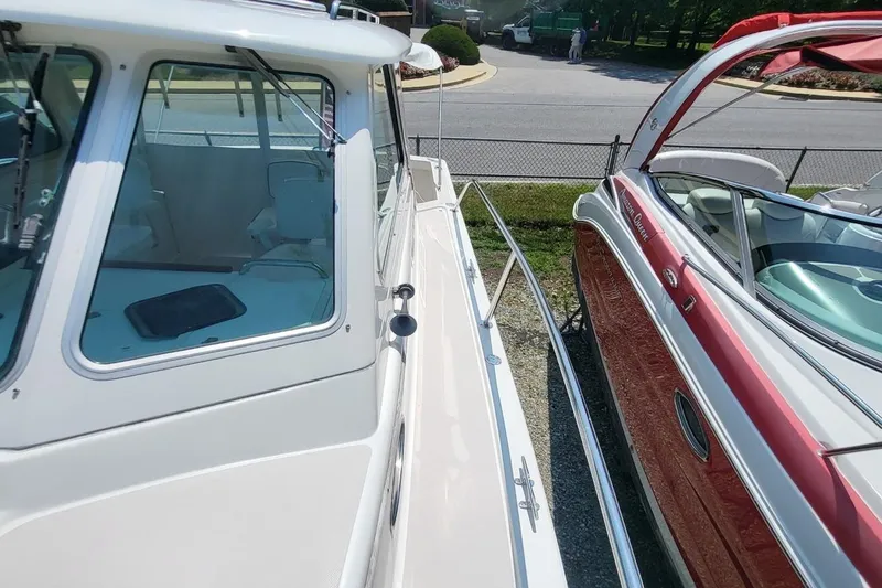 Slide: The Image of 2006 Back Cove 29 boat docked beside a red vessel, showcasing sleek design and windows. - 13