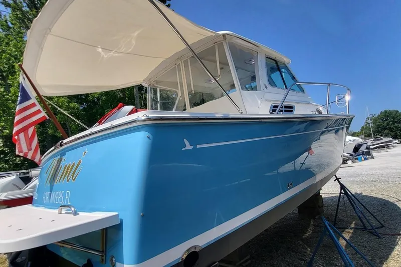 Slide: The Image of 2006 Back Cove 29 boat with blue hull, docked outdoors under clear sky. - 8