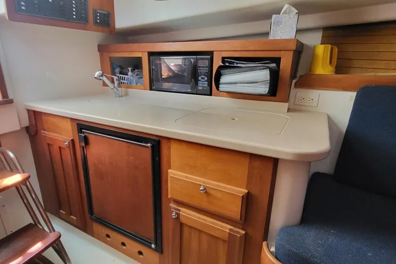 Slide: The Image of 2006 Back Cove 29 boat interior with kitchenette, featuring a microwave, sink, and storage cabinets. - 19