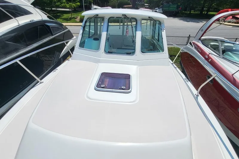 Slide: The Image of 2006 Back Cove 29 boat with sleek white deck and cabin, docked between other boats. - 11