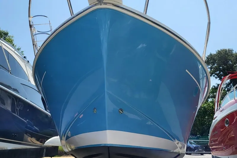 Slide: The Image of 2006 Back Cove 29 boat with blue hull, docked between other vessels. - 2