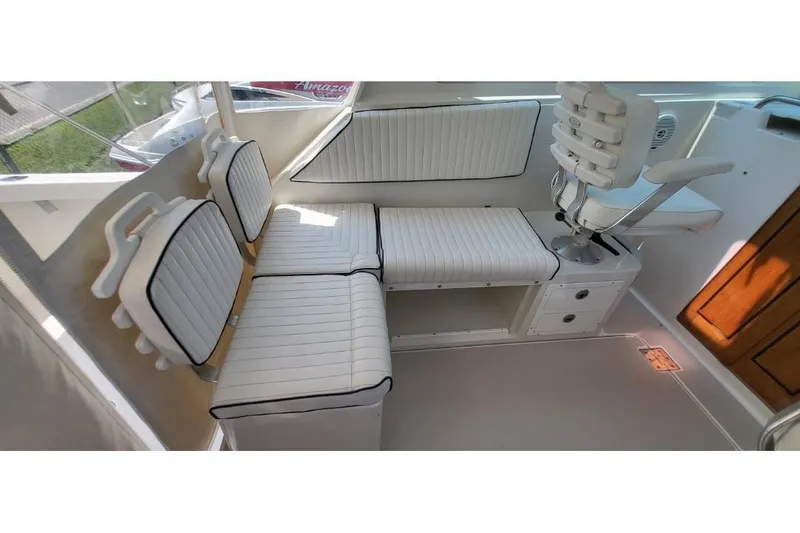 Slide: The Image of Interior seating of a 2006 Back Cove 29 boat, featuring white cushioned seats and a captain's chair. - 15