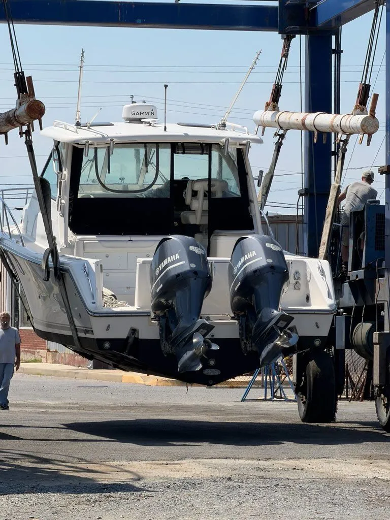 Slide: The Image of A 2009 Pursuit OS 3450 boat being lifted out of the water by a crane. - 9