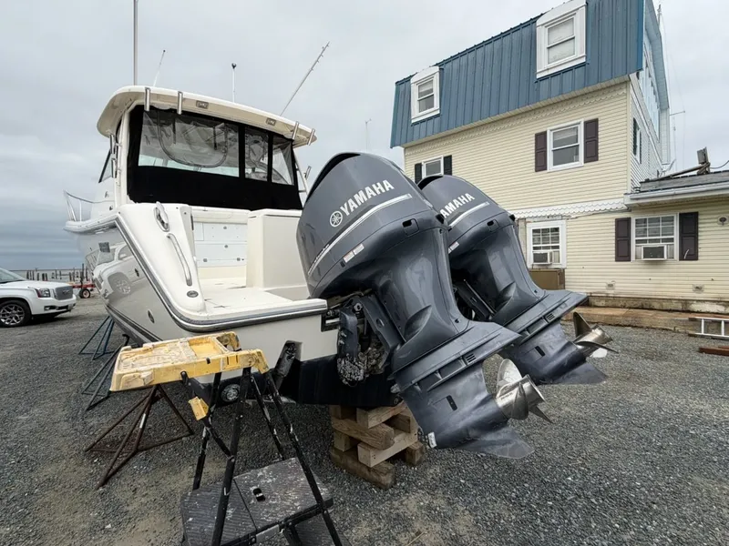 Slide: The Image of 2009 Pursuit OS 3450 with twin Yamaha engines, on a gravel lot next to a building. - 3