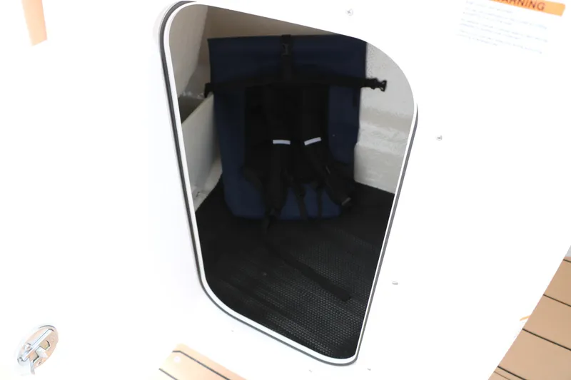Slide: The Image of Storage compartment inside 2025 Chaparral 23 SSi boat, featuring safety equipment. - 36