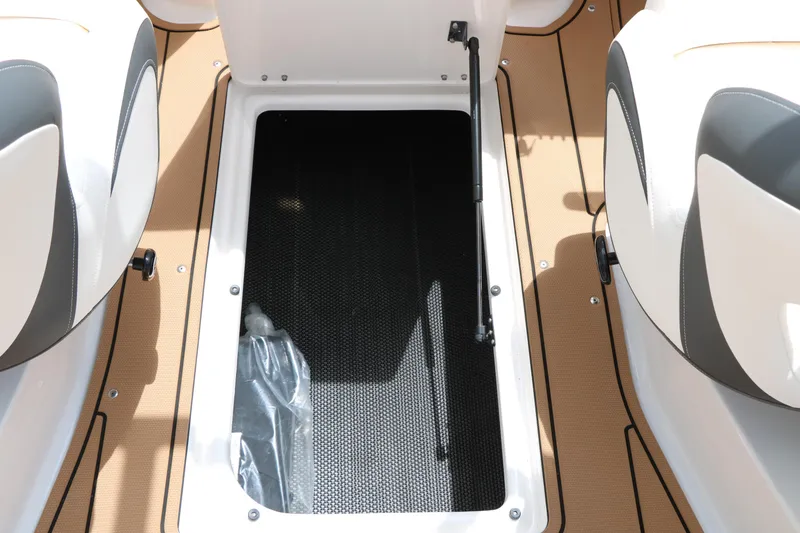 Slide: The Image of 2025 Chaparral 23 SSi boat storage compartment with open hatch and cushioned seating. - 34