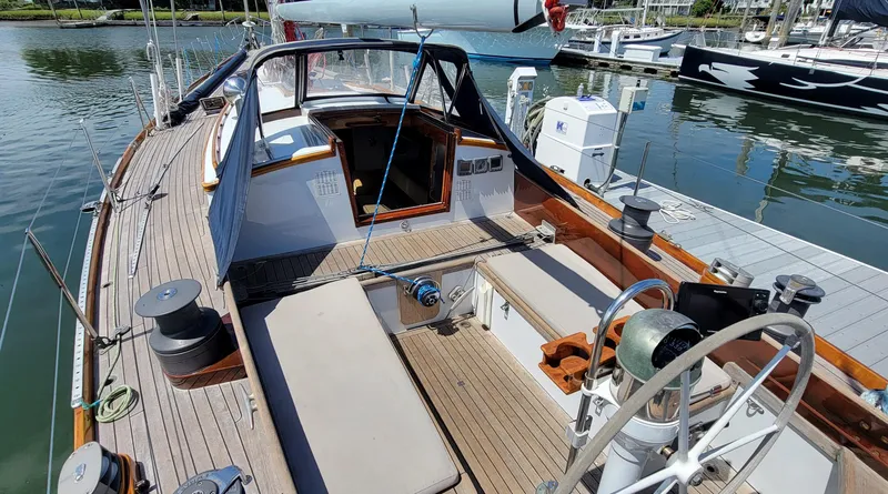 Slide: The Image of Sailboat deck with steering wheel and benches, docked at a marina. - 9