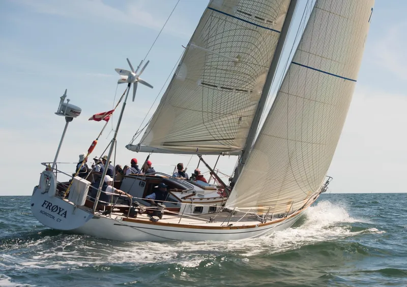 Slide: The Image of A sailboat navigates through gentle waves. It has white sails and a group of people on board. - 6