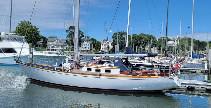 Slide: The Image of A classic sailboat docked in a marina, surrounded by other boats and houses in the background. - 3