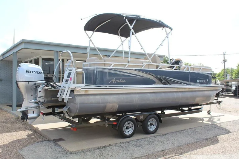 Slide: The Image of 2021 Avalon VLS Quad Lounge 22 FT pontoon boat with Honda outboard motor on trailer. - 2