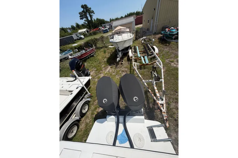 Slide: The Image of 2000 Regulator 26 Forward Seating boat with dual engines in a yard setting. - 4