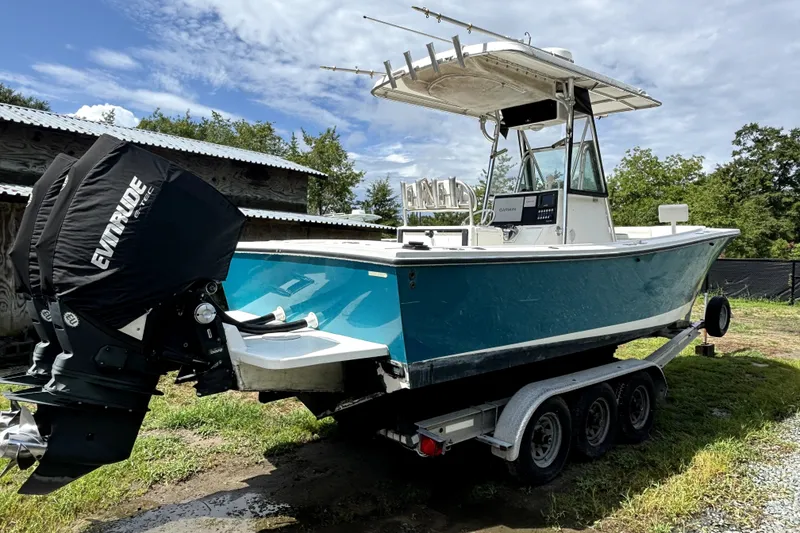 Slide: The Image of 2000 Regulator 26 Forward Seating boat on trailer, featuring Evinrude engine, outdoors. - 18