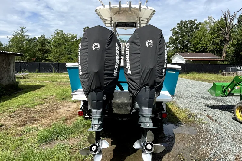 Slide: The Image of 2000 Regulator 26 Forward Seating boat with Evinrude engines, parked outdoors. - 19
