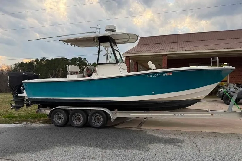 The Image of 2000 Regulator 26 Forward Seating boat on trailer, parked outdoors near a building. - 1